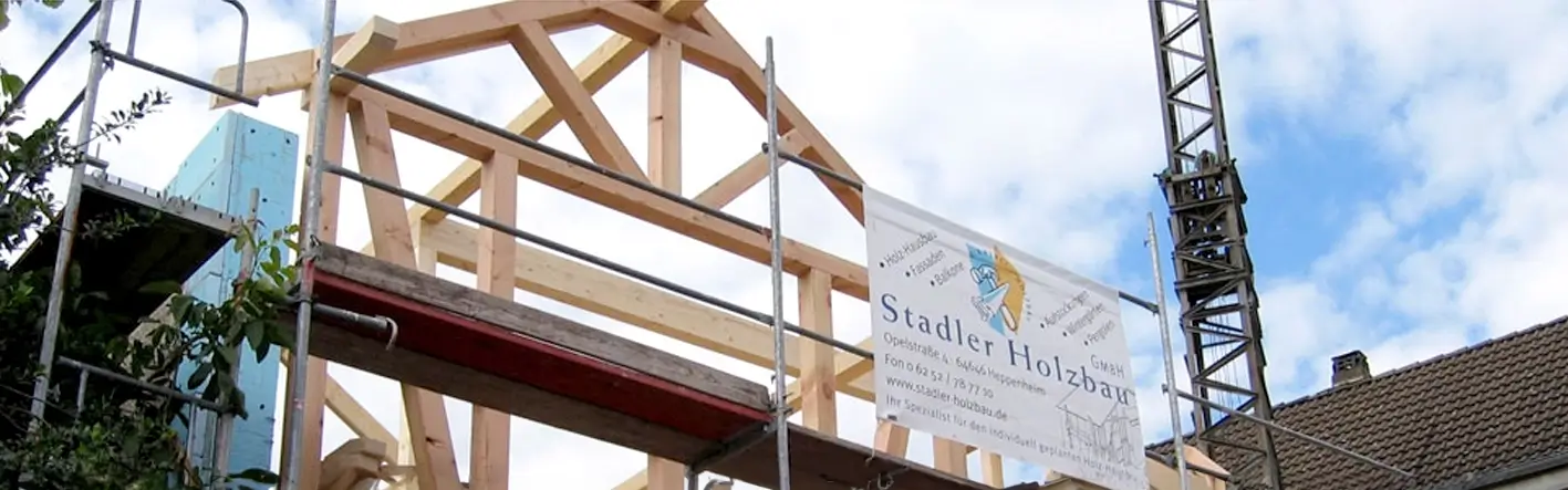 Ein neuer Dachstuhl mit Gerüst und einem Werbeplakat der Firma Stadler